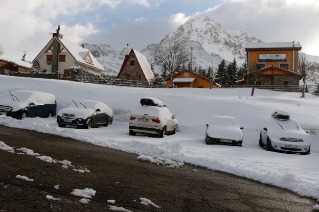 Arriba, coches cubiertos por la nieve en La Raya, en Aller. A la izquierda, caballos bajando de los Lagos. 