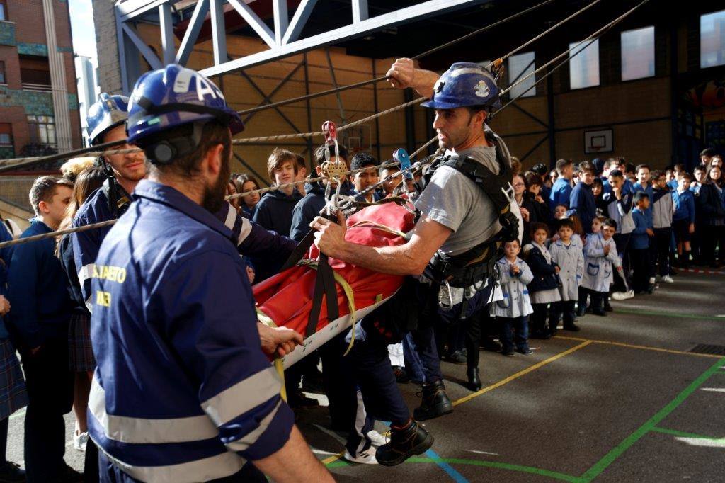 La Brigada Minera ha acudido este jueves al Colegio Nazaret de Oviedo para mostrar a los alumnos el trabajo que realizan. Los miembros del cuerpo simularon un descenso en tirolina con la colaboración de uno de los estudiantes.