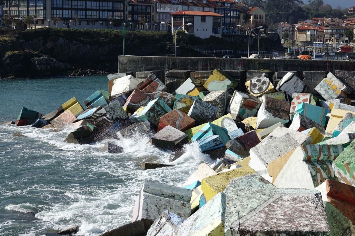 La mar baña los Cubos de la Memoria, ubicados en el espigón del puerto de Llanes, con parte de la villa al fondo. 