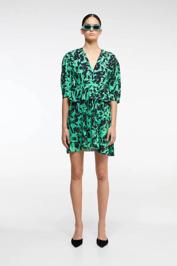 Vestido corto con detalle de volante en la cintura y estampado floral sobre fondo verde de Sfera, 14,35 euros.