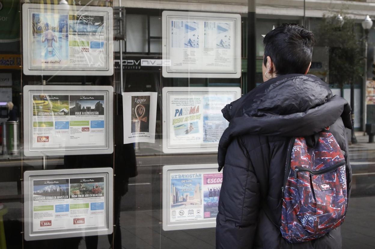 Una persona consultaba las distintas ofertas en una agenda de viajes, ayer, en Gijón. 