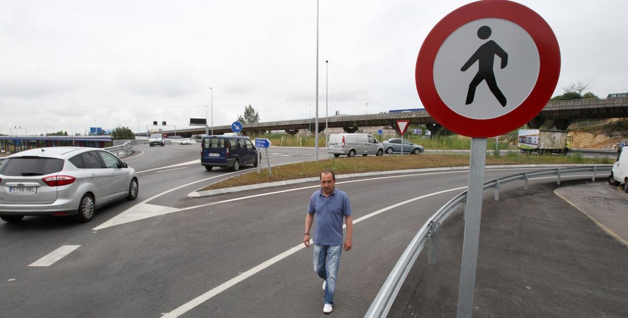 Un peatón pasea por el arcén en la rotonda de Cerdeño. 