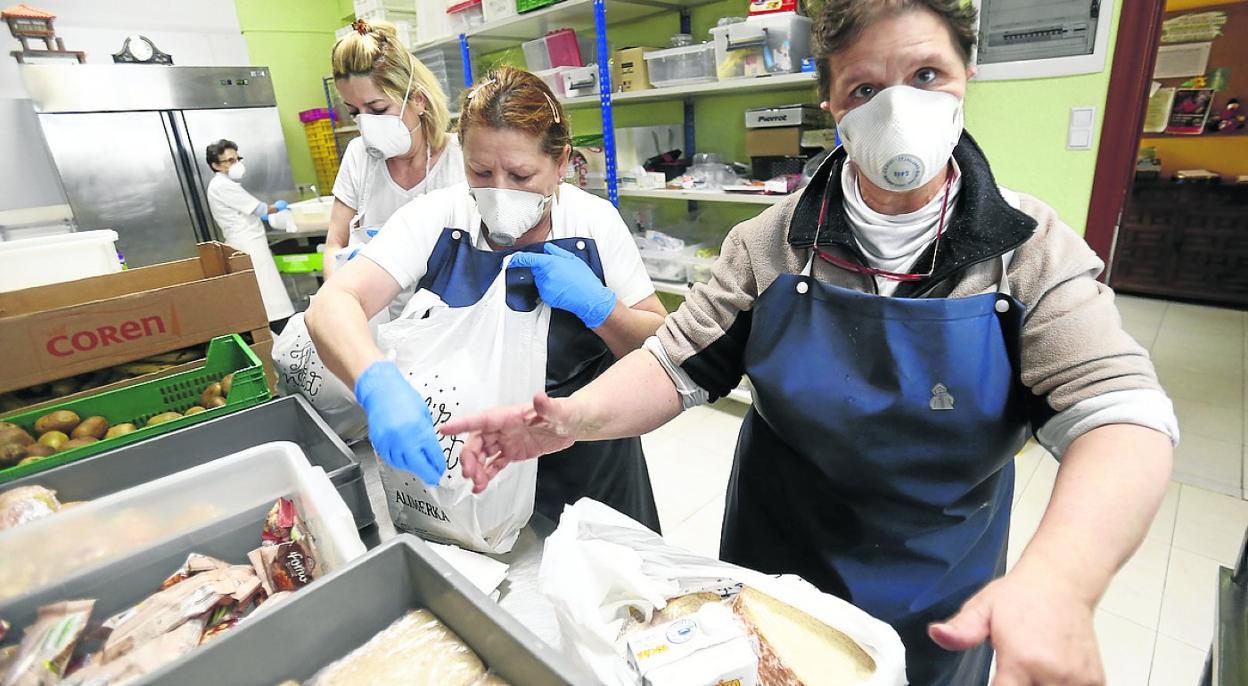 Las empleadas de la Cocina Económica meten la comida y la cena del día en bolsas. 