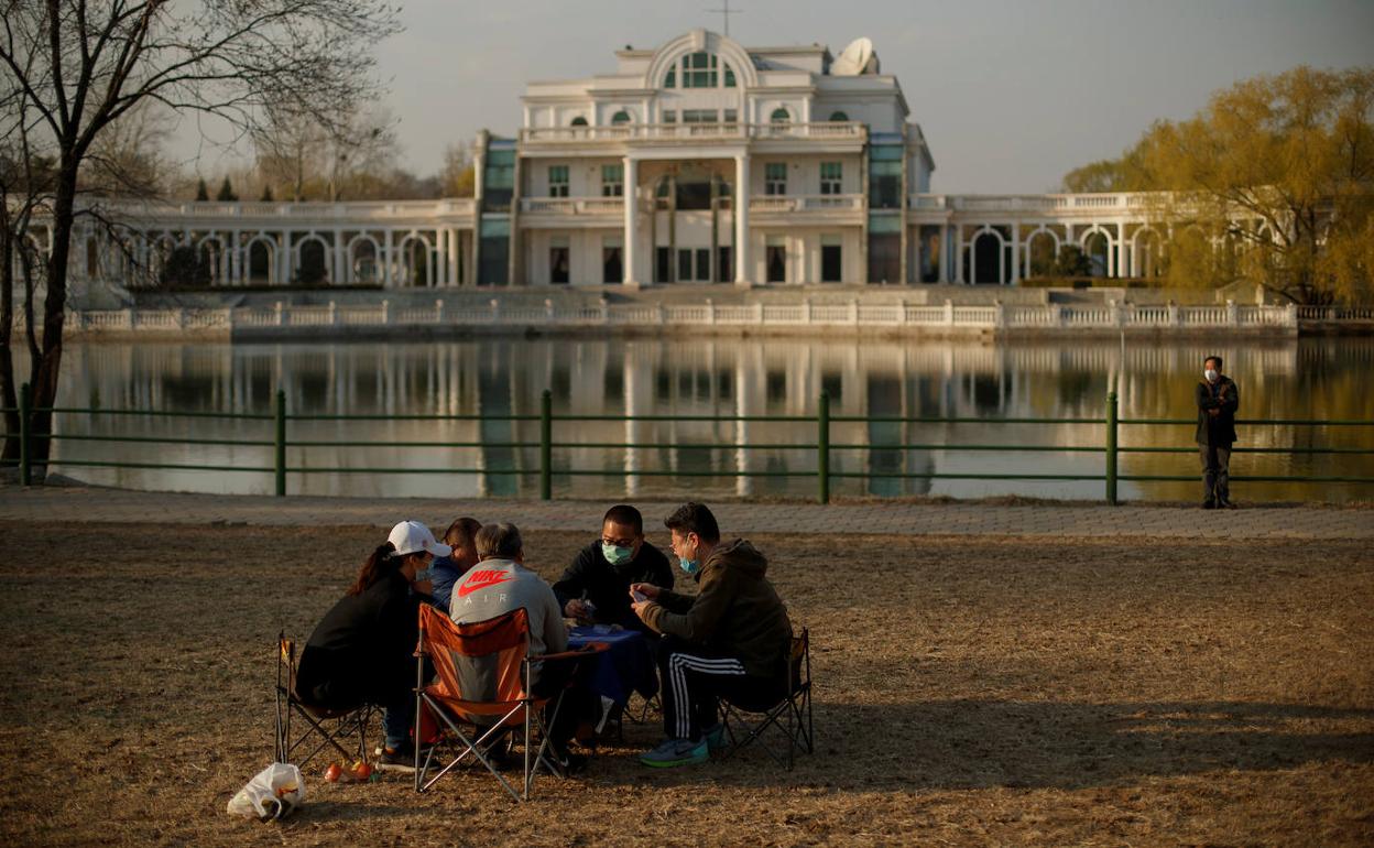 Un grupo de amigos juega a cartas al aire libre, en un parque de Pekín. 