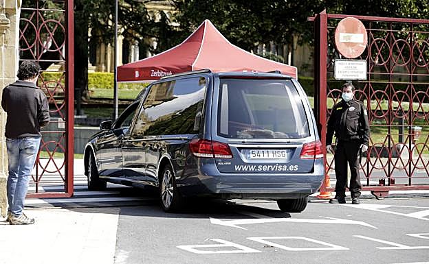 Un coche fúnebre entra a un cementerio.