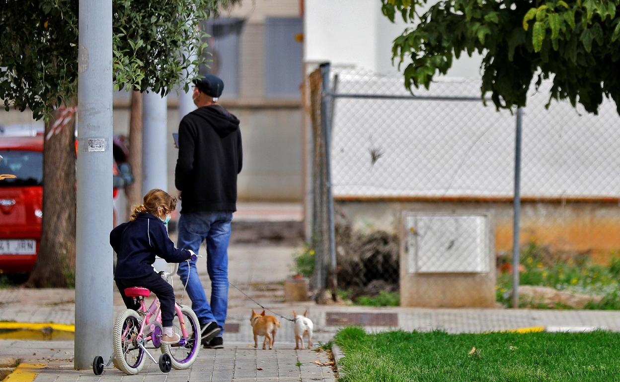 Un padre junto a su hija pasea a sus dos perros en una calle de Valencia. 