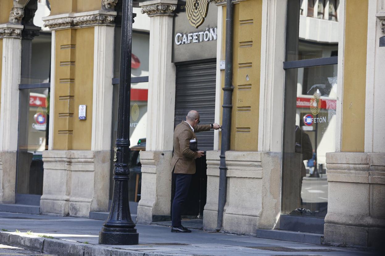 Un hostelero cierra el portón del Cafetón de la plazuela de San Miguel, en Gijón. 