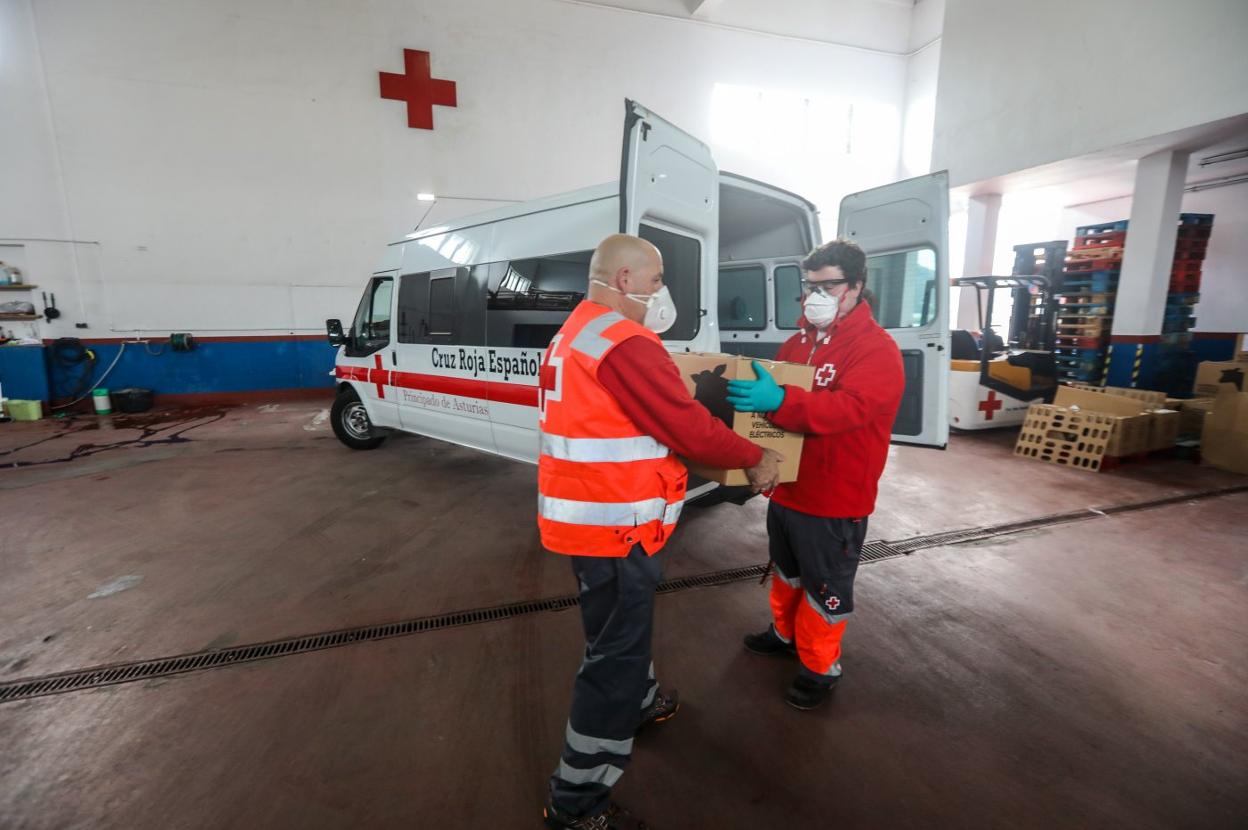 Voluntarios de Cruz Roja Avilés cargan alimentos, medicinas y kits de higiene en una ambulancia para llevarlos a varios domicilios. 