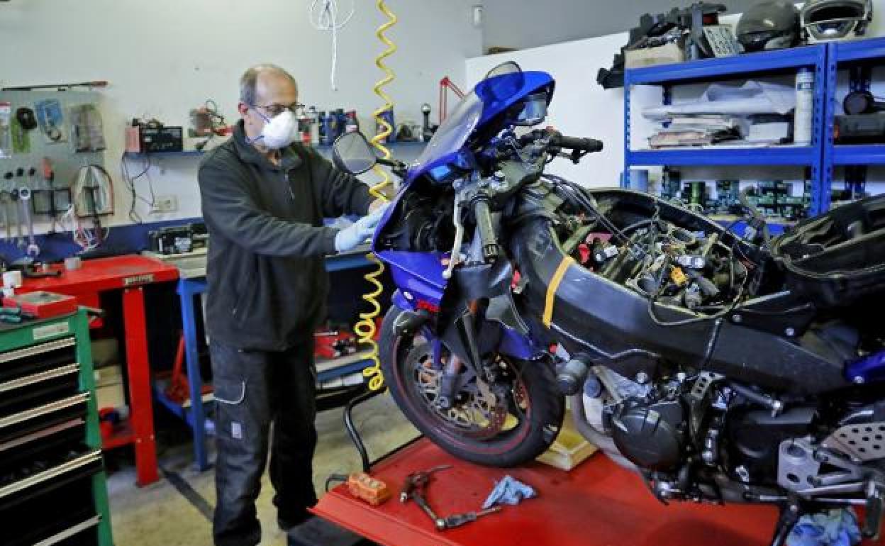 Un mecánico trabaja en la reparación de una moto en un taller de Gijón. 