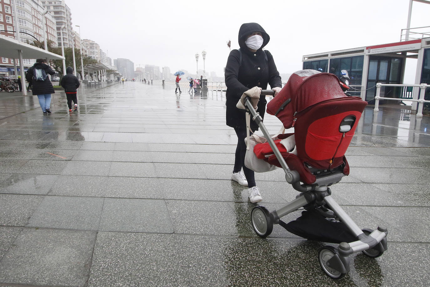 Primeros paseos bajo el orbayu en Gijón de los más pequeños