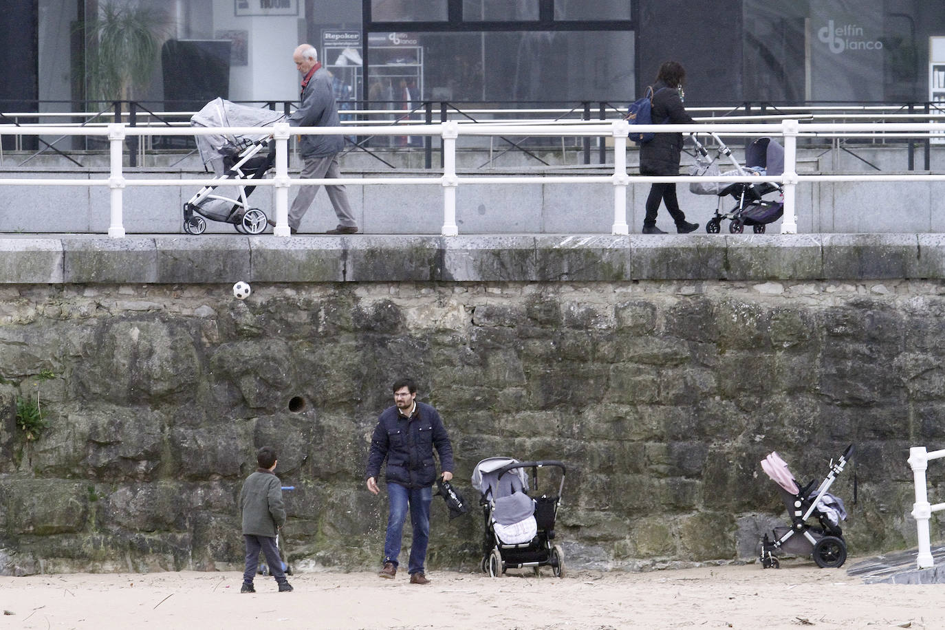 Primeros paseos bajo el orbayu en Gijón de los más pequeños