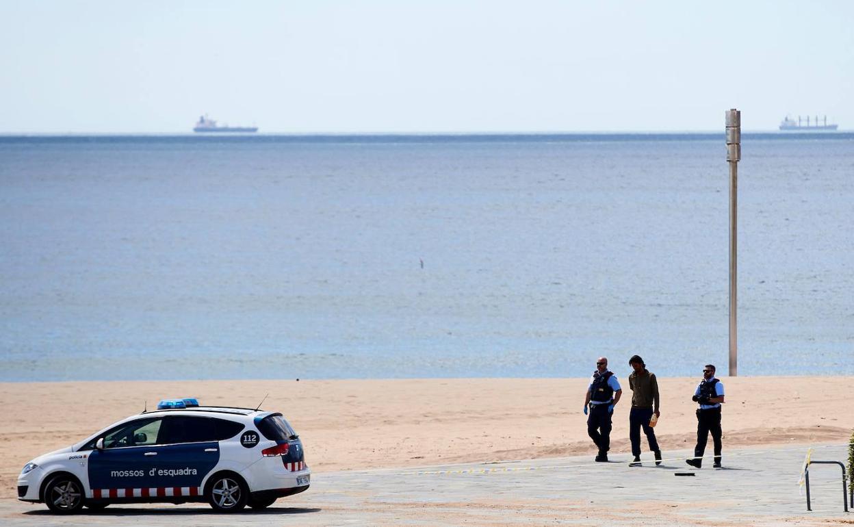 Una patrulla de los mossos de escuadra identifican a un hombre en la playa la Mar Bella de Barcelona, 