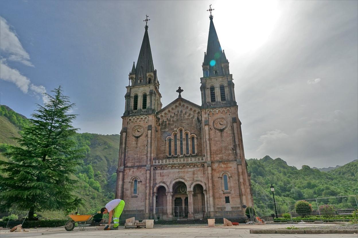 Un operario colocando ayer las nuevas losas de la explanada de la basílica de Covadonga. El abad observa junto a operarios los avances de los trabajos. 
