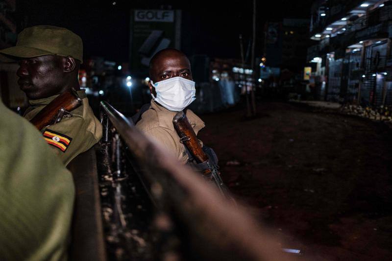 Varios policías ugandeses y miembros de una fuerza paramilitar compuesta por civiles patrullan por las noches en la ciudad de Kampala para asegurarse del cumplimiento del toque de queda nocturno decretado el 14 de abril en Uganda para tratar de detener la propagación del coronavirus. 