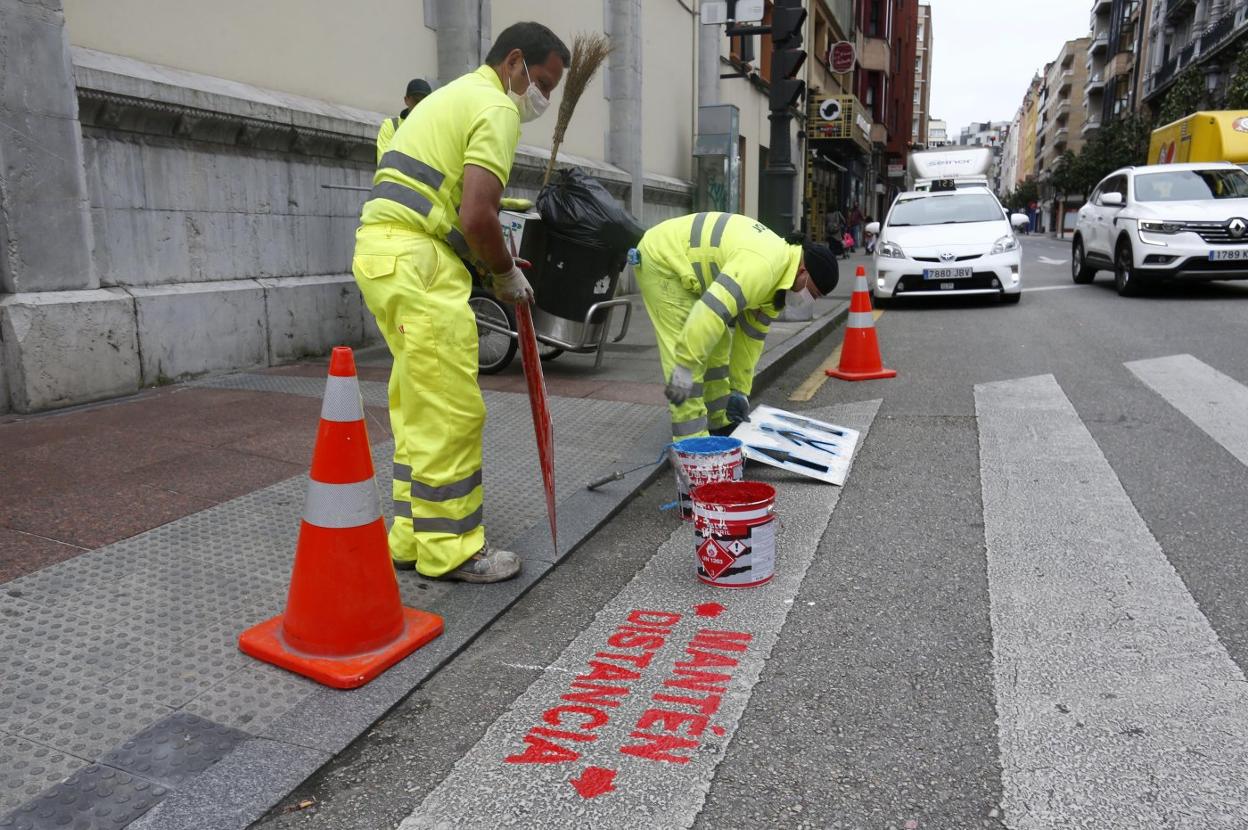 Unos operarios colocando las nuevas indicaciones en la calle Independencia. 