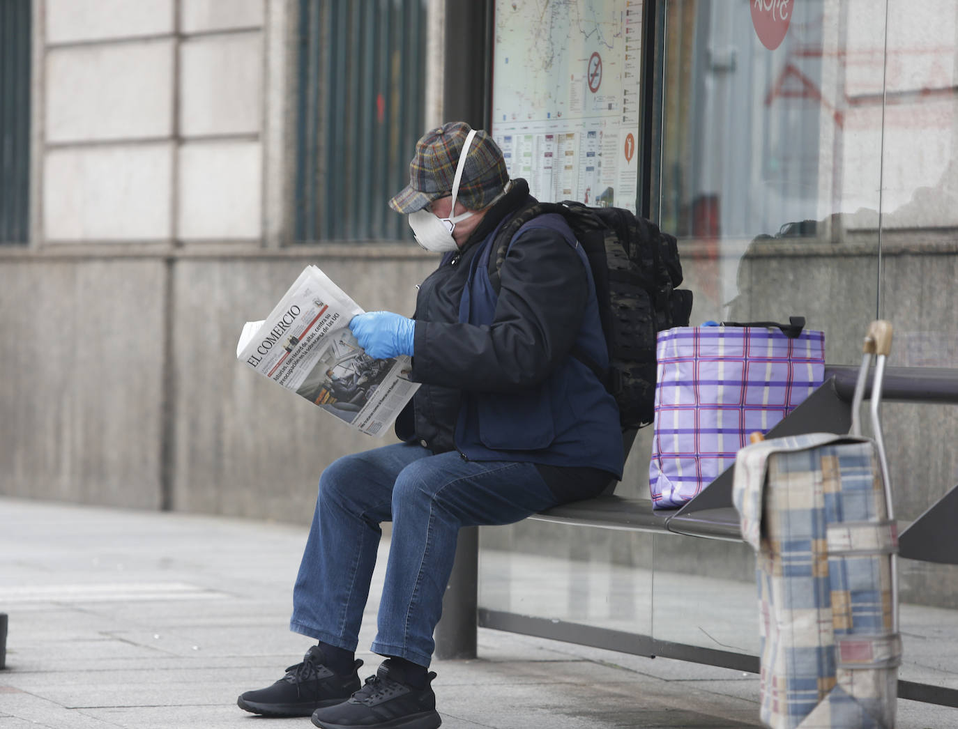 02 de abril. Gijón | Un hombre con mascarilla y guantes lee el diario EL COMERCIO. 