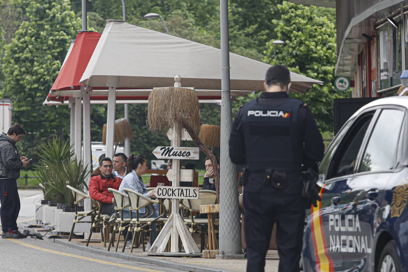 13 de mayo. Gijón | Agentes de la Policía Nacional supervisan la distancia social y de las mesas en una terraza. 