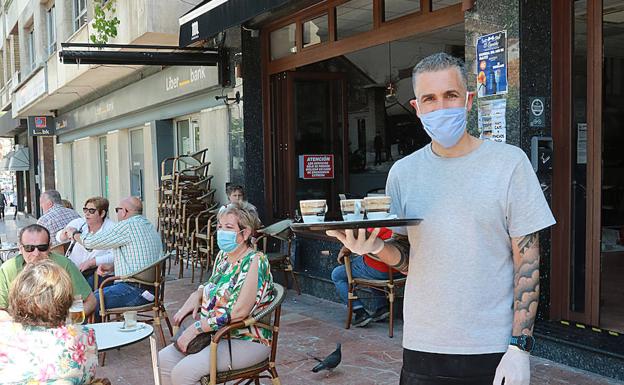 José Luis González El Capricho de Patrick's & Martins (Pola de Lena)Con mascarilla y guantes para servir las consumiciones en la terraza. 