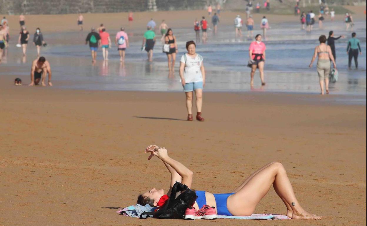 Una mujer disfruta del sol en la Playa de San Lorenzo de Gijón. 