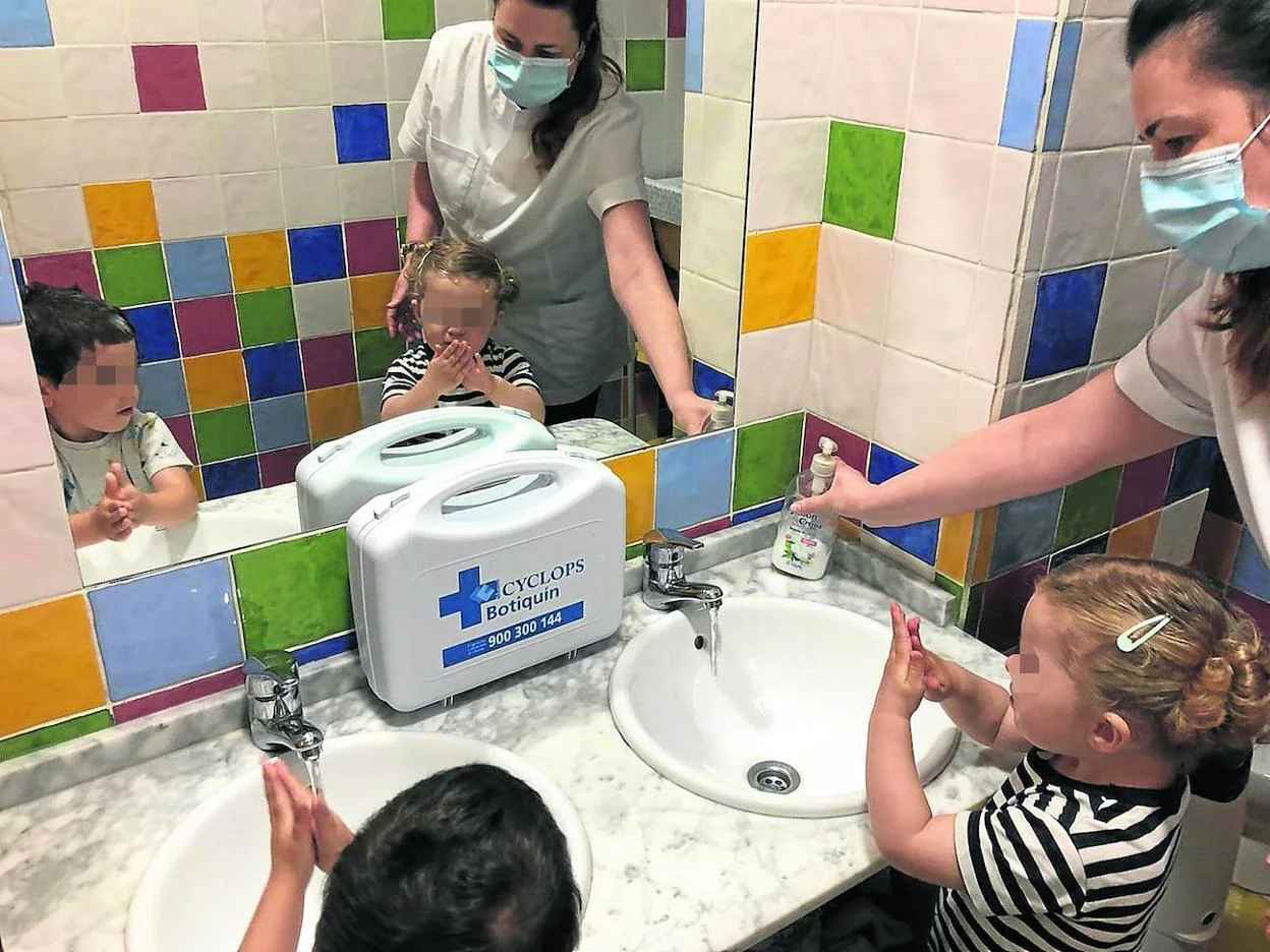 Inés Suárez, directora de la guardería Barrio Sésamo de Gijón, ayuda a dos pequeños a lavarse las manos con agua y jabón. 