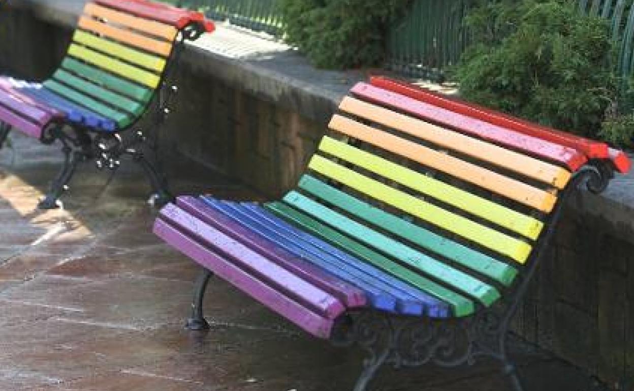 Imagen de archivo de unos bancos pintados con los colores de la bandera arcoíris. 