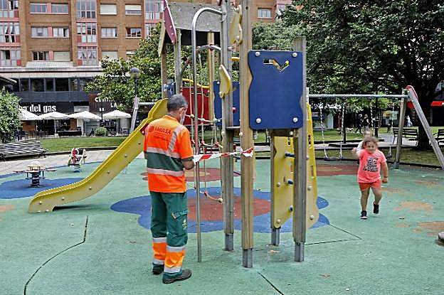 Un operario de Emulsa procede a precintar las instalaciones de juegos del parque de la Fábrica del Gas, en La Arena. 