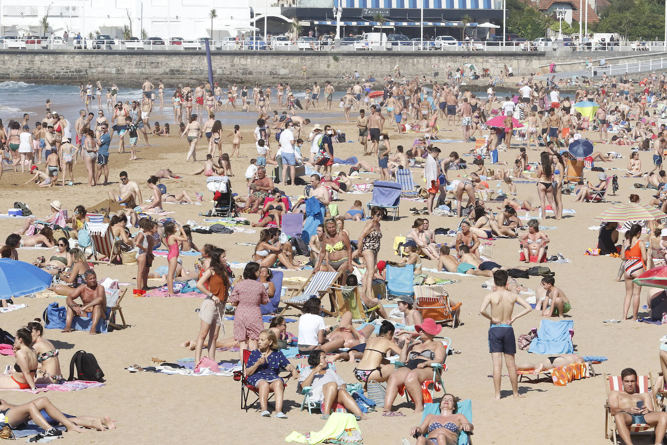 Los arenales gijoneses han vuelto este martes a llenarse de gente que ha querido pasar una nueva jornada de intenso calor tumbado en la arena o refrescándose en el agua.