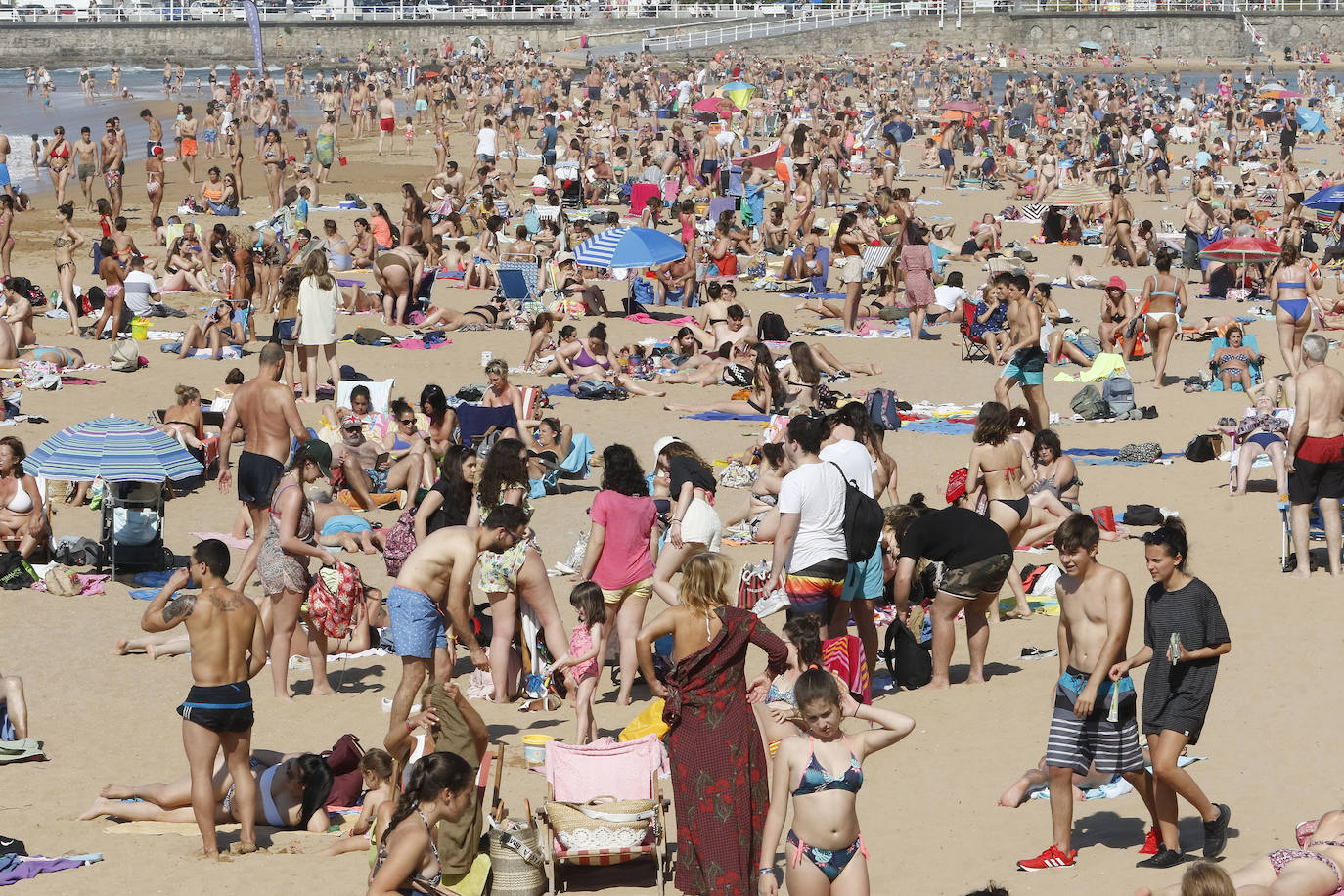 Los arenales gijoneses han vuelto este martes a llenarse de gente que ha querido pasar una nueva jornada de intenso calor tumbado en la arena o refrescándose en el agua.