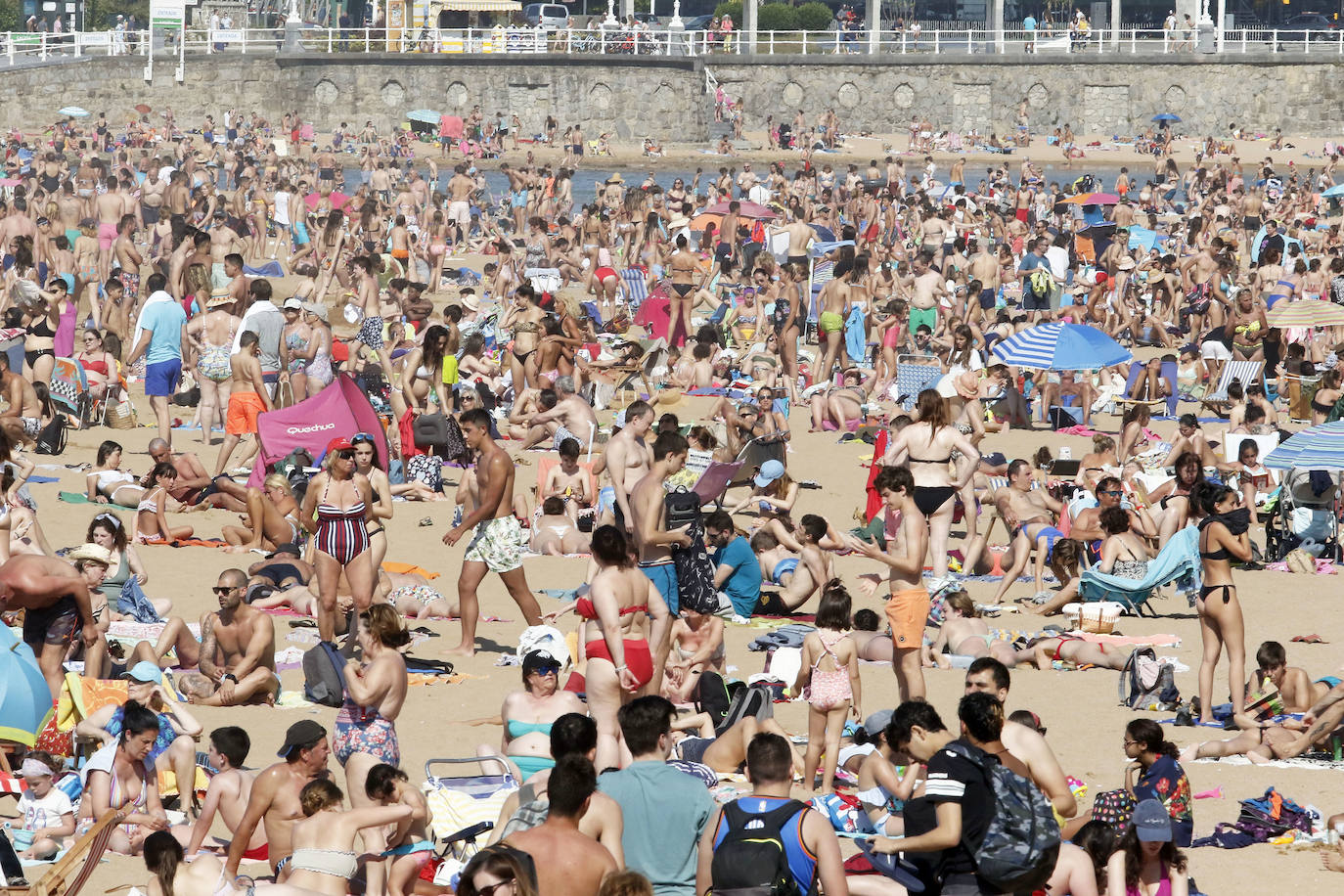 Los arenales gijoneses han vuelto este martes a llenarse de gente que ha querido pasar una nueva jornada de intenso calor tumbado en la arena o refrescándose en el agua.