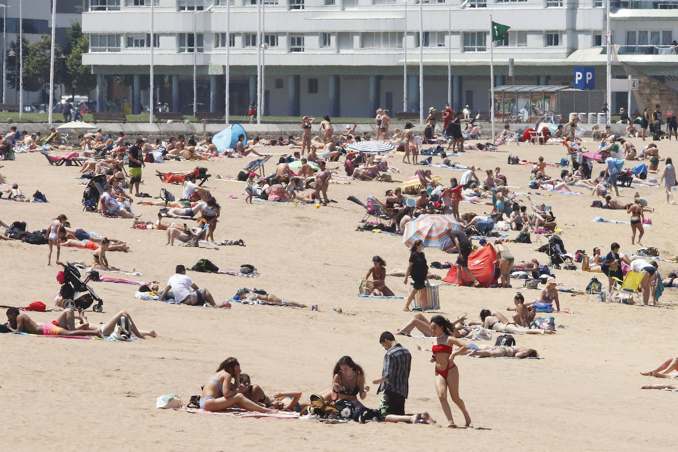 Los arenales gijoneses han vuelto este martes a llenarse de gente que ha querido pasar una nueva jornada de intenso calor tumbado en la arena o refrescándose en el agua.
