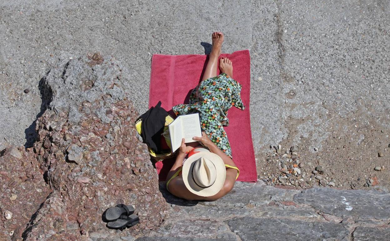 Una mujer leyendo un libro en la playa. 