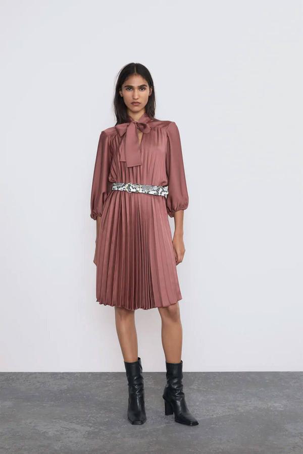 Vestido plisado con cinturón y cuello subido con lazada de Zara, 29,99 euros.