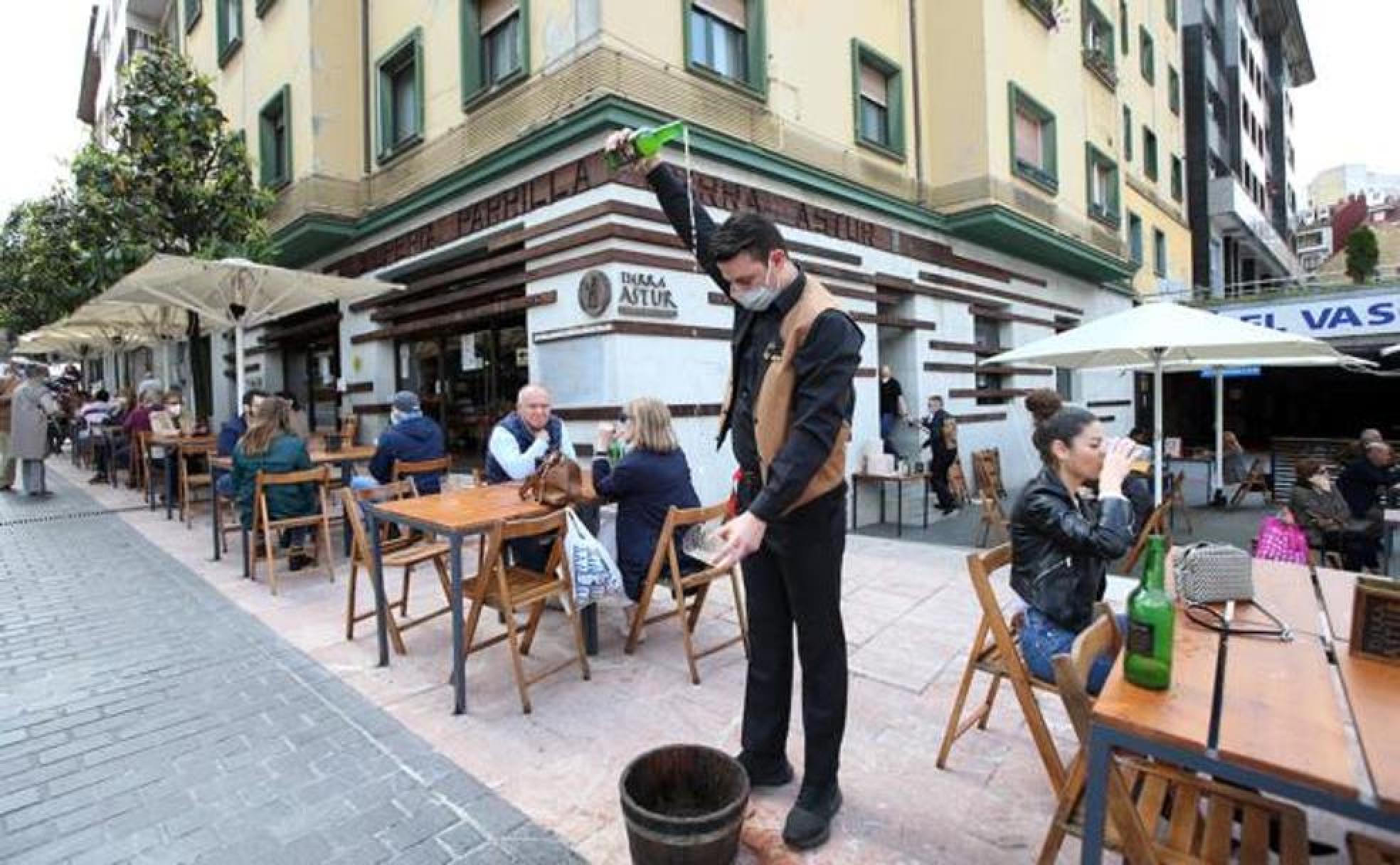 Un camarero escancia un culín en una terraza de Oviedo. 