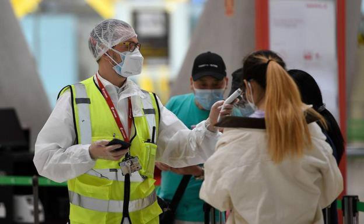 Un empleado del aeropuerto de Barajas toma la temperatura a una pasajera.