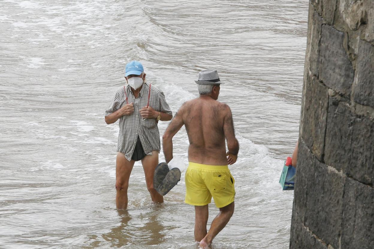 Un hombre, con mascarilla dentro del agua, en la playa de San Lorenzo.