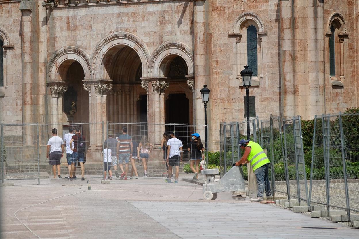 Un operario da los últimos retoques a la explanada mientras los visitantes se dirigen a la basílica. 