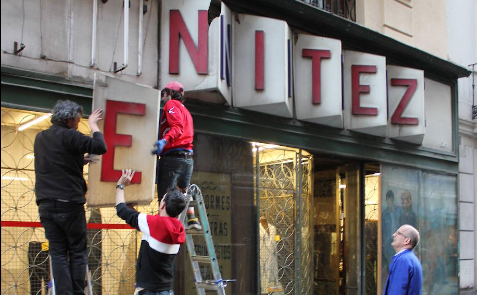 'Activistas' de la Red desmontan el letrero de la histórica sastrería Casa Benítez, en Chueca (Madrid).