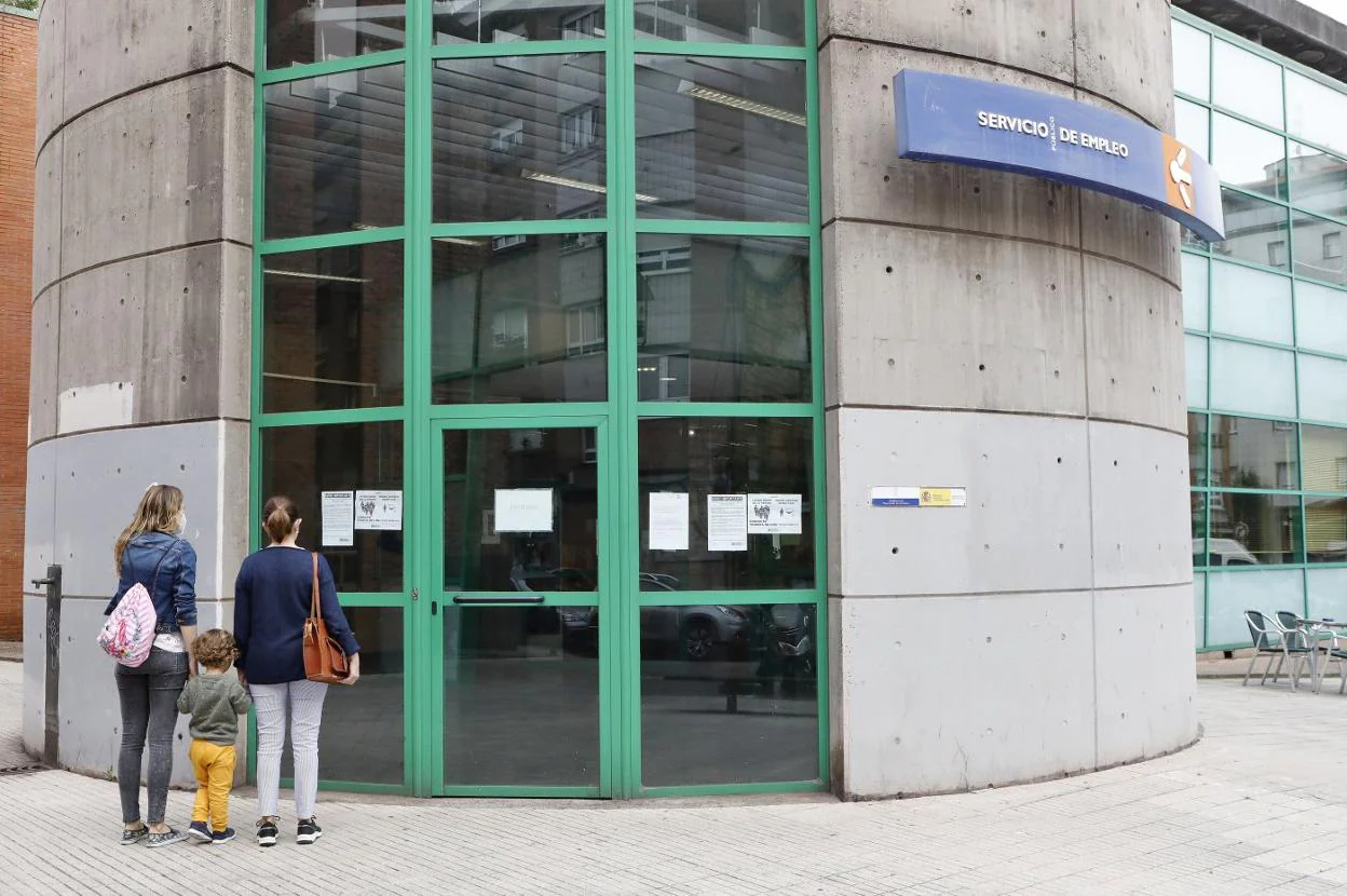 Dos mujeres con un niño, delante de una Oficina de Empleo en Gijón. 