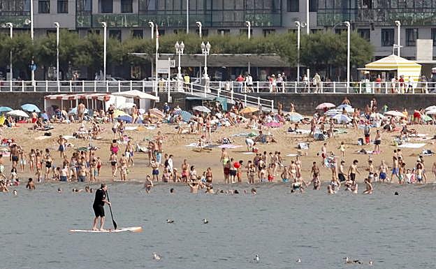 Un practicante de pádel surf, y la playa vista desde el barco. 