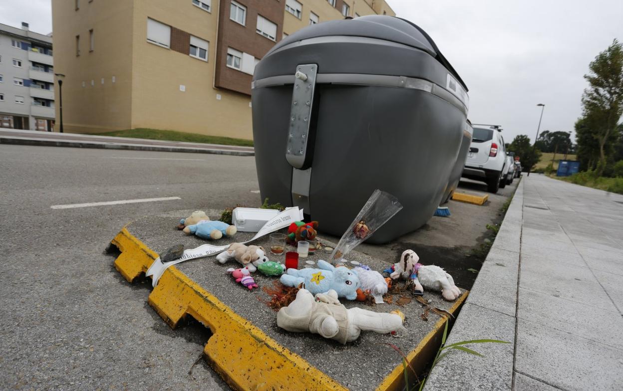 Peluches y flores junto al contenedor de Nuevo Roces. 