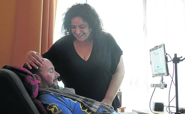 Arturo Rodríguez Ollero y su mujer, Mónica Riera, en su piso de Gijón, desde donde se comunica con un ordenador.