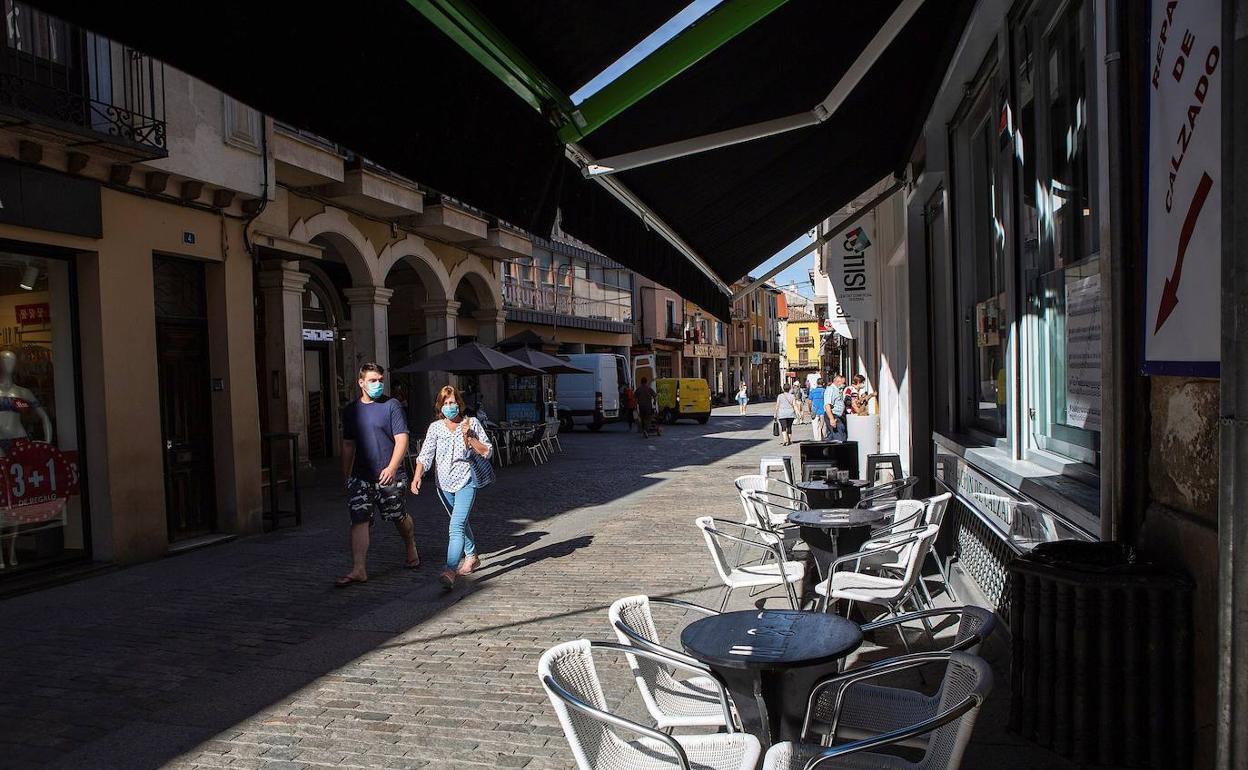 Dos personas caminan al lado de una terraza vacía en un bar de Burgos.