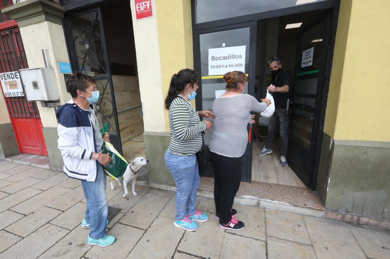 Tres personas, ayer haciendo cola para recoger alimentos en la Fraternidad de Francisco. 