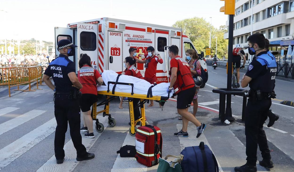 Policías, sanitarios y socorristas, durante la asistencia a la mujer que sufrió la caída en el Muro. 