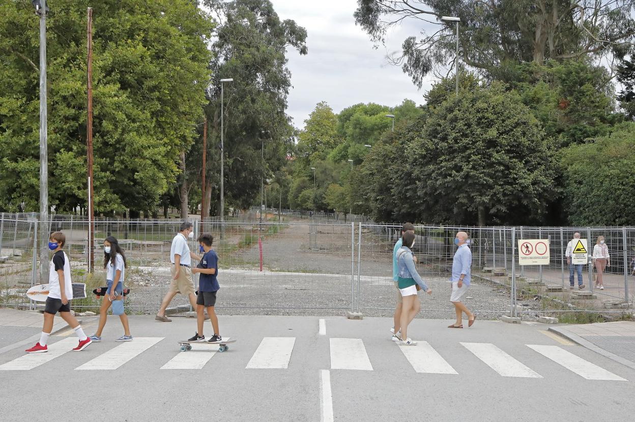 Paseantes ante la avenida de El Molinón, vallada y con el suelo allanado, ya sin actividad desde hace meses.