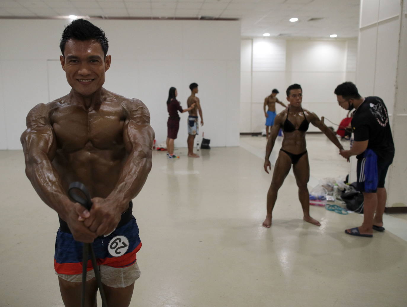 Protegidos con pantallas de plástico, decenas de concursantes compiten en el certamen de culturismo 'Mr. Tailandia' en Bangkok