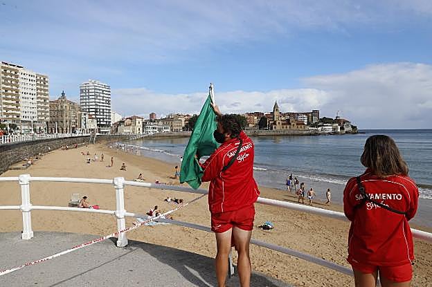 Un socorrista coloca la bandera verde en la Escalerona. 