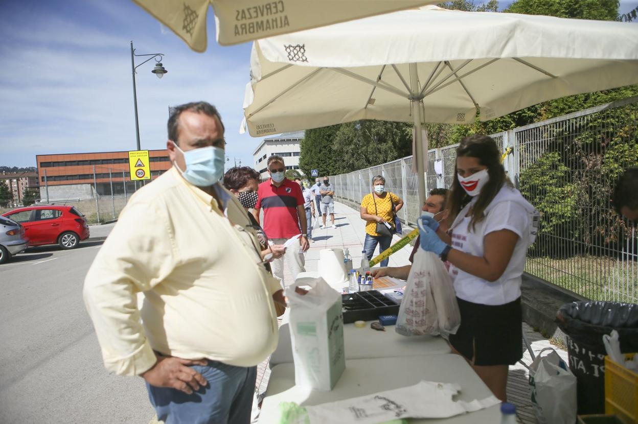 Un vecino de Lugones recoge sus lotes de bollo, sidra y vaso. 