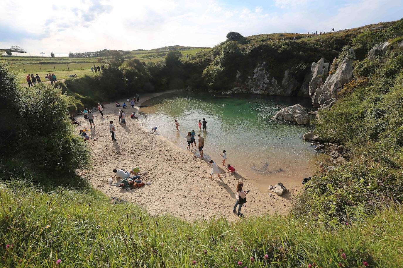 Un enclave similar es la playa de Gulpiyuri, uno de los mayores atractivos turísticos de Llanes y el oriente de Asturias. La formación de esta playa se debe a la inundación de una dolina kárstica, una depresión originada por el hundimiento del techo de una cavidad subterránea. El mar penetra por las galerías subterráneas, dando forma a un pequeño arenal “utilizable en la bajamar y que asemeja una piscina de aguas marinas durante la pleamar”. Por esto, y “a pesar de su diminuto tamaño, se trata de una singularidad geomorfológica de primer orden", ya que se trata de "una playa sin mar situada cien metros tierra adentro”. 