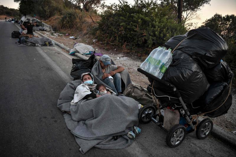 Miles de personas pasan la noche a la intemperie en los alrededores del devastado campo de refugiados de Moria (Lesbos), el más grande de Grecia, a la espera de ser trasladados. Las carreteras que rodean el campo, en el que malvivían 13.000 personas, están repletas de familias que con lo poco que les ha quedado se han instalado en la calzada o en alguna cercana al campo que no ha sido destruida por el incendio del martes por la noche; un incendio que comenzó simultáneamente en varios puntos del campo, poco después de que las autoridades comunicaran a 35 personas que habían dado positivo de covid-19 y que debían ser aisladas. 